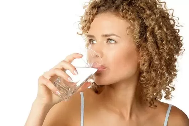 The girl follows the lazy diet, drinks a glass of water before eating